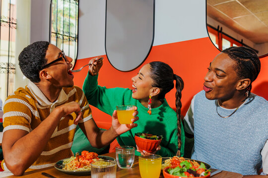 Playful friends sharing food and laughter in vibrant restaurant