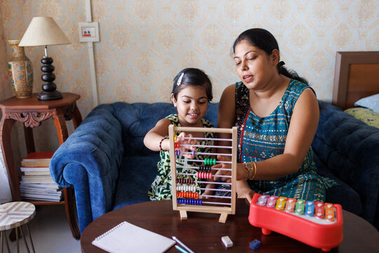Mother teaching her little daughter to count with abacus