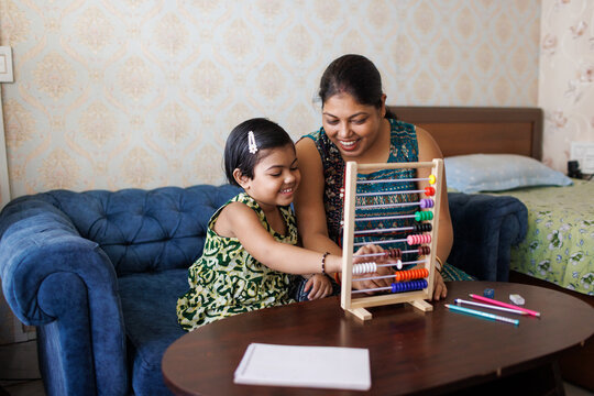 Mother teaching her little daughter to count with abacus