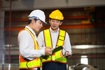 Asian man team engineer worker working control sheet metal roof tile roll forming machine at metal sheet profiling factory. Industrial production. Unity and teamwork