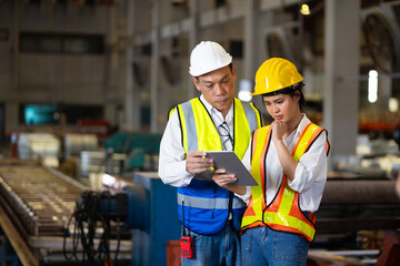 Trainee. Asian Factory worker training to  apprentice colleague on production line in Heavy Industry Manufacturing Facility. Instructor with Trainee working at factory