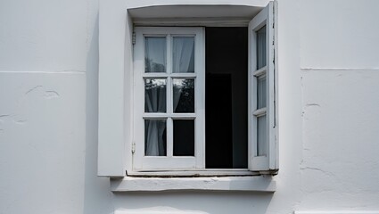 Fototapeta premium Open white window framed against a textured white wall with sheer curtains softly billowing in a gentle breeze creating a serene atmosphere.