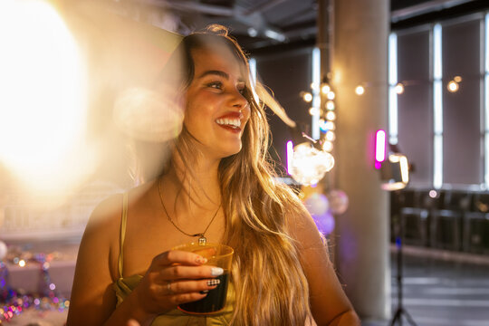 Joyful Woman at a Vibrant Party with Drink in Hand