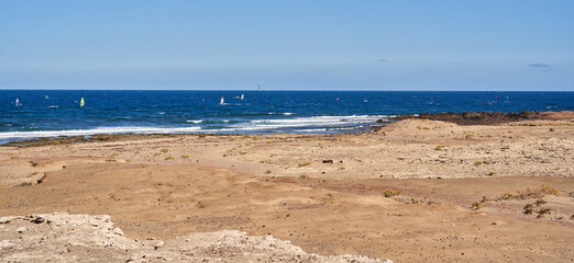 Windsurfers on ocean near arid coast in Tenerife........