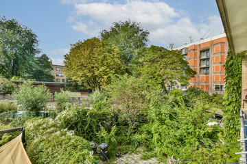 A vibrant view of a lush garden surrounded by trees and residential buildings, showcasing nature's beauty in an urban setting.