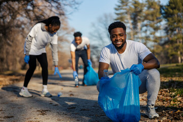 Portrait of eco aware black volunteer smiling at camera while having cleanup initiative in nature...