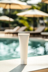 Fototapeta premium White tube of sunscreen against the background of a swimming pool with sun loungers and umbrellas under bright sun