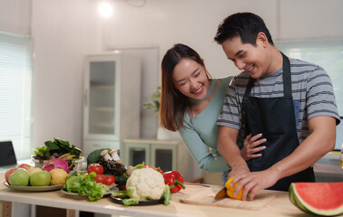 Asian couple having fun cooking together in modern kitchen