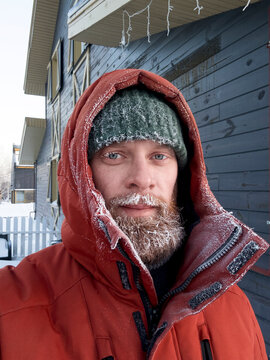 Happy bearded man wearing red winter jacket enjoying snowy landscape