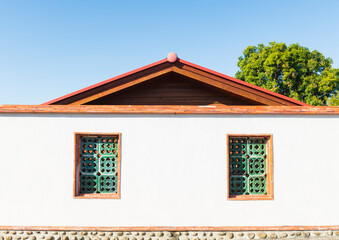 White - walled Building with Green Patterned Windows and Red Roo