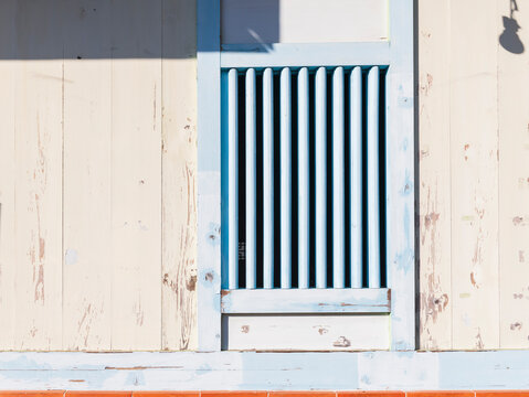 Light colored Wooden Wall with Blue framed Window and Orange Til