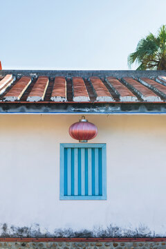 White walled Building with Blue framed Window and Red Chinese La