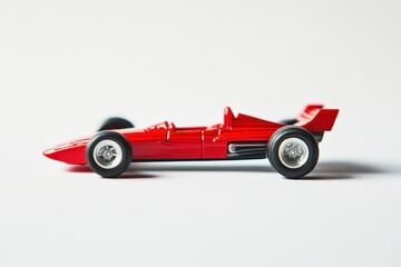 A small bright red race car toy sits against a white background