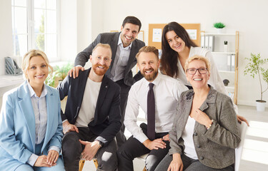 Group portrait of cheerful people colleagues men and women looking at camera and smiling indoors....