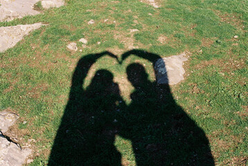 Couple of lovers make heart by hands outdoors.