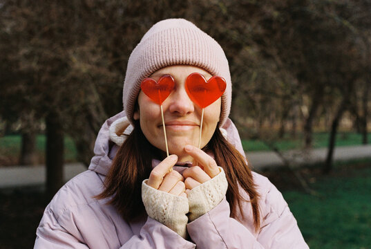 Portrait of smiling woman with red lollipops in the shape of heart.