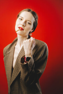 Stylish Woman in Retro Blazer with Cigarette Against Red Background
