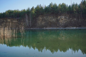 deep lake with green clean water in the forest and rocks. mirroring trees in water