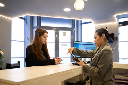 Patient paying for dental treatment with contactless payment at reception desk