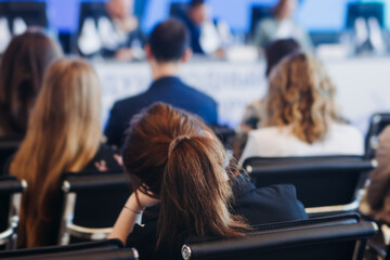 Audience at the modern conference hall listens to panel discussion, people on a congress together...
