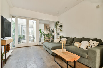 A stylish modern living room featuring a cozy sofa, wooden coffee table, and vibrant indoor plants, creating a warm and inviting atmosphere.