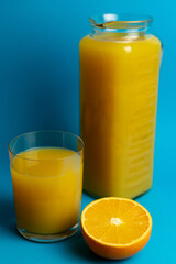 Glass of orange juice in glass close-up. Cut oranges on the table.