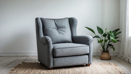 Fototapeta premium Cozy light gray armchair positioned on a warm beige rug against a soft white wall with a green plant accentuating the serene atmosphere.
