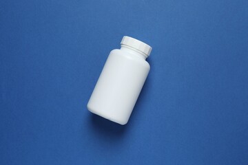 White bottle on blue background, top view