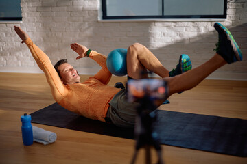 Personal trainer recording online blog tutorial while exercising at home.