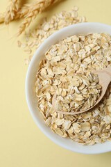 Composition with oatmeal flakes on beige background. Cooking breakfast