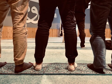 People standing in mosque during prayer, rear view shot.
