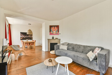 A stylish modern living room featuring a gray sofa, wooden flooring, and contemporary art. The space is well-lit and inviting, showcasing a blend of comfort and elegance.
