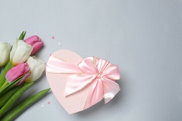 Beautiful fresh tulips with gift box on gray background