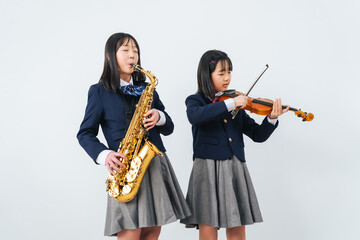 サックスとバイオリンを練習する女子学生グループ