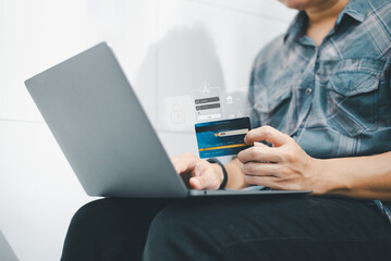 Man holding credit card and using laptop for online payment, shopping, banking, or secure login on digital platform.