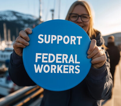 A woman smiling while holding a blue circular sign that says "Support Federal Workers" in bold white letters. A social activism and labor rights concept.