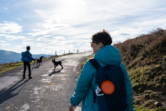 Hikers walking with dogs on mountain road in Spain