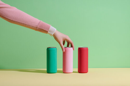 Hand Reaching for Soda Can Against Colorful Background