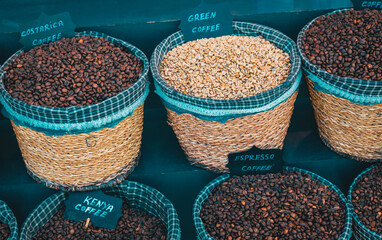 A market display of coffee beans in woven baskets, featuring roasted espresso, green coffee, and specialty beans from Kenya and Costa Rica. A vibrant selection for coffee lovers.