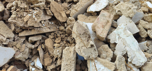 Pile of broken bricks, concrete, and rubble with scattered wooden planks and white plaster fragments; rough textures and earthy tones dominate the scene;