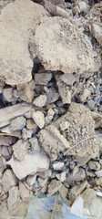 Pile of dry, broken soil chunks with small rocks and scattered debris; rough texture with cracks...