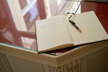 Open notebook with handwritten notes and a pen on a glass-topped wooden hotel desk. Hauts-de-France, France