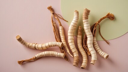 Obraz premium Dried ginseng roots arranged artistically on pastel pink background with green accent, showcasing natural textures and organic shapes.
