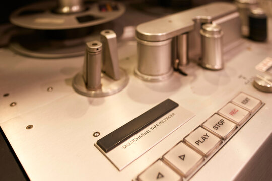 Close-up of vintage multichannel tape recorder with control buttons and reels in a studio.