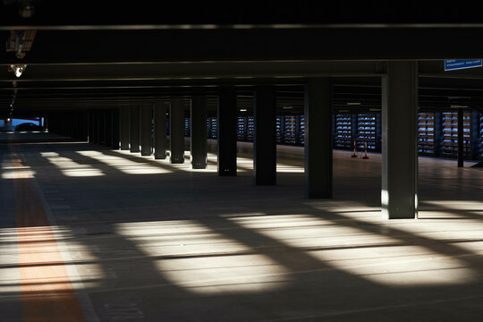 Empty underground parking garage with pillars and sunlight creating patterns on the floor. Berlin, Germany