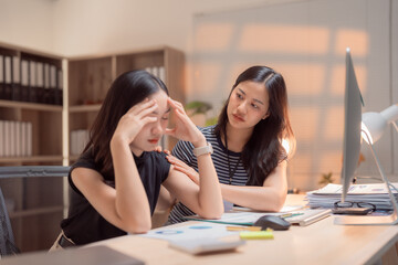 Asian businesswomen collaborating in an office, providing support and empathy as one woman comforts...