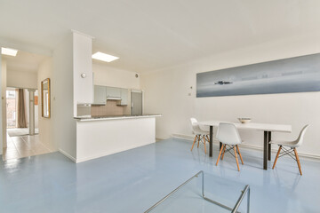 A sleek and modern interior featuring a minimalist dining area with white chairs and a simple table. The soft color palette enhances the spacious feel of the room.