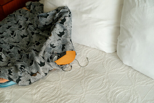 Intricate patterned fabric partially covering an object on a white textured bedspread. Miami, FL, USA