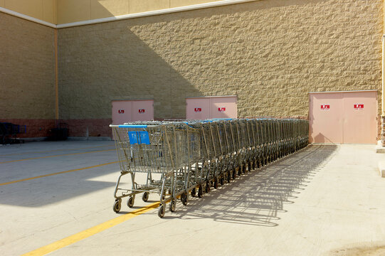 Long row of shopping carts lined up outside a store against a brick wall. California, USA