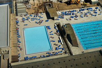 Aerial view of two outdoor swimming pools with sunbathers and lounge chairs on a sunny day. Barcelona, Spain